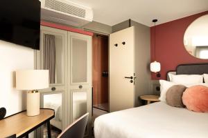 a hotel room with a bed and a desk at La Dépendance in Paris