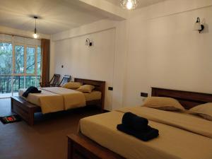 a bedroom with two beds and a window at Isha Unity Cottage in Nallathanniya +21 photos