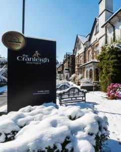 een bord in de sneeuw naast een bank bij The Cranleigh Boutique in Bowness-on-Windermere