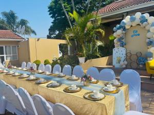 a long table with white chairs and a blue and white decorations at Ulifalodge & functions in Durban