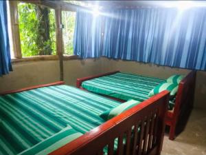 two beds in a room with blue curtains at River cottage Demodara in Demodera +83 photos