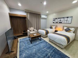 a hotel room with two beds and a tv at المهيدب للشقق المخدومه 2 in Al Ahsa