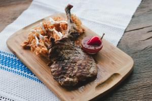 a steak on a cutting board with pasta and a sauce at Hanul Teilor in Dăneşti