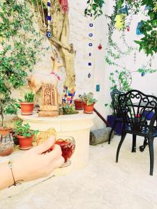 a person holding a bowl of food in a room with potted plants at Cleopatra Antique Hotel in Urfa