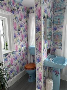 a bathroom with a blue sink and a toilet and a wallpaper at Greylands Guest House in Llandrindod Wells +50 photos