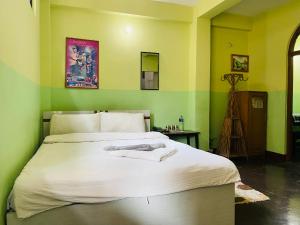a bedroom with a bed with white sheets and green walls at Three Peaks Inn in Kathmandu +39 photos