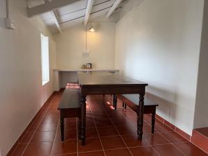 a dining room with a wooden table and benches at Ellem House in Kotagiri