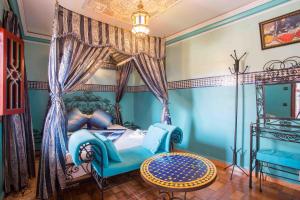 馬拉喀什的住宿－里亞德哈姆紮住宿加早餐旅館，一间卧室配有一张天蓬床、一把椅子和一张桌子