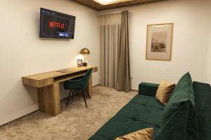 a living room with a green couch and a desk at Hanul Teilor in Dăneşti