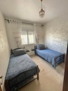 a bedroom with two beds and a chandelier at ADORA Apartment in Tangier