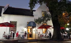 a group of people sitting at tables outside of a building at The Stellenbosch Hotel in Stellenbosch