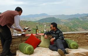 Um homem está a dar um copo de vinho a outro homem. em Itmenaan Estate in the Himalayas em Almora