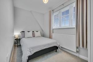 a white bedroom with a bed and a window at Lovely 2-Bed House with parking in Broomfield +16 photos
