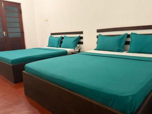 two beds in a room with blue pillows at Mango Three Resort in Anuradhapura