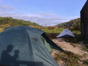 two tents in a field with the shadow of a person at Ditrek Adventure in Ðại Lào