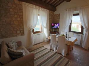 een woonkamer met een tafel en stoelen en een televisie bij Modern holiday home in Foligno - Loc with pool in Case Vecchie