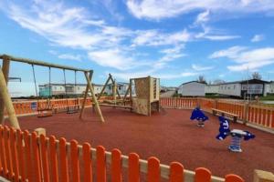 an empty playground with an orange fence and swings at Seaside Lodge Haven in St Osyth in Jaywick Sands