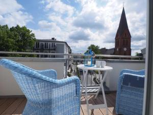 a balcony with two chairs and a table and a church at Kirchenplatz 6 Apartment 17 in Warnemünde