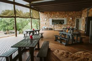 a restaurant with wooden tables and a stone wall at Matatane Camp - Babanango Game Reserve in Babanango