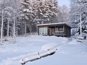 a cabin in the snow in front of a forest at Villa lehto in Kuusamo