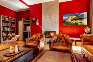 a living room with red walls and leather furniture at Das Karl August in Fohnsdorf