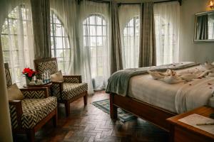 a bedroom with a bed with two chairs and windows at Saab Royale Resort in Kajiado +70 photos
