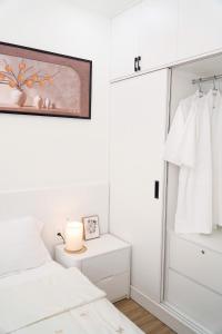 a white bedroom with a bed and a dresser at KNV Apartment in Thu Dau Mot