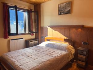 een slaapkamer met een bed met een houten hoofdeinde en een raam bij Chimenea, confort moderno y madera - Falcó 2 in Pla de l'Ermita