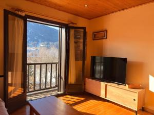 een woonkamer met een tv en een groot raam bij Chimenea, confort moderno y madera - Falcó 2 in Pla de l'Ermita