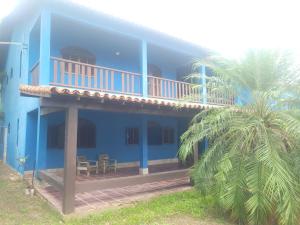 a blue house with a balcony and a palm tree at Casa Espaçosa em Unamar in Cabo Frio