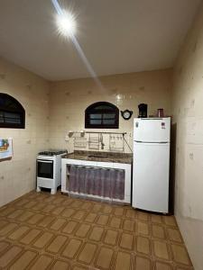 a kitchen with a stove and a white refrigerator at Casa Espaçosa em Unamar in Cabo Frio