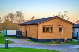 a wooden house with a black roof at Finest Retreats - Heron Luxury Lodge in Bourn