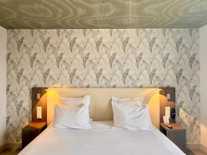 a bed with white pillows in a bedroom with a wallpaper at Best Western Hotel Restaurant Ile de France in Château-Thierry