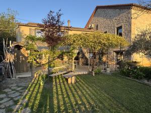 a garden with benches in front of a building at Maison Bruno Di Salvio in Les Vans