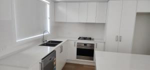 a white kitchen with a sink and a stove at Room In Dubbo With Queens Beds in Dubbo