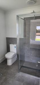 a bathroom with a toilet and a glass shower at Room In Dubbo With Queens Beds in Dubbo +33 photos