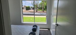a person laying on a bed looking out a window at Room In Dubbo With Queens Beds in Dubbo