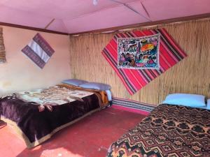 a bedroom with two beds and a blanket on the wall at Casa de Yolanda en Uros in Puno +2 photos