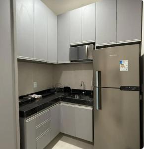 a kitchen with white cabinets and a stainless steel refrigerator at Flat 11 Condomínio Ibiapaba Camocim in Camocim