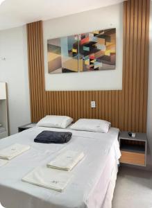 a large bed with white sheets and a painting on the wall at Flat 11 Condomínio Ibiapaba Camocim in Camocim