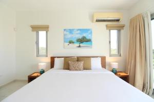 a bedroom with a white bed and two windows at Ocean View Mansion 8 min to Palm Beach in Noord