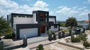 a black and white house with a fence at Ocean View Mansion 8 min to Palm Beach in Noord