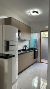 a kitchen with a white refrigerator and a sink at Beautiful Cozy Beach House Accommodation in Guaratuba