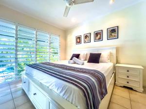 a bedroom with a large white bed and a window at Escape To Mango House in Airlie Beach