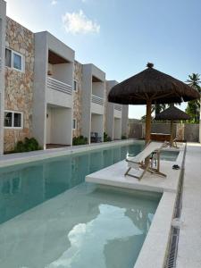 a swimming pool with an umbrella and a chair at Apartamento A03 - Curimã in Passo de Camarajibe
