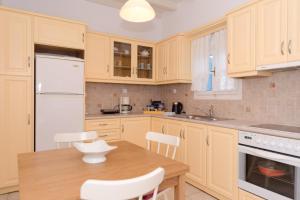 a kitchen with a wooden table and white appliances at Folia in Agia Marina