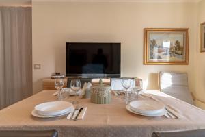 a table with plates and wine glasses and a television at Trilo Ciasa Brìma in Carano