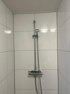 a shower with a hose attached to a white tile wall at Luxe Chalet Inn Otterlo op de Veluwe aan het Water! in Otterlo +8 photos