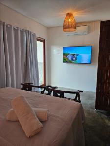a bedroom with a bed and a table and a tv at Casa Entre Coqueiros in Tamandaré