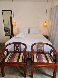 a bedroom with a bed with two chairs at Casa Entre Coqueiros in Tamandaré